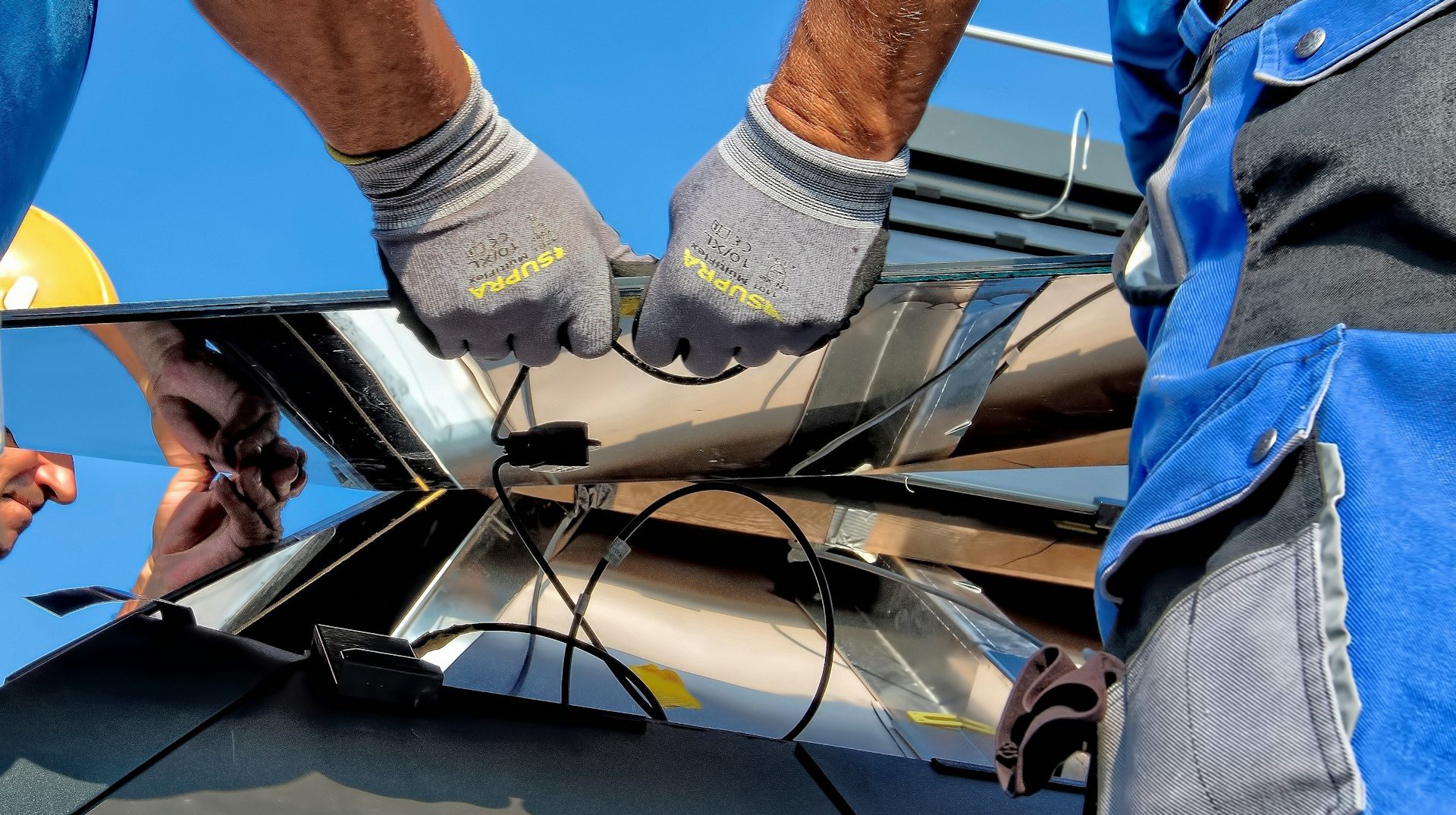Electrician's gloved hands connecting solar panel wiring